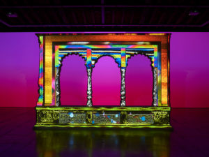 Intricately carved pavilion with basically whole spectrum of color projected onto it.