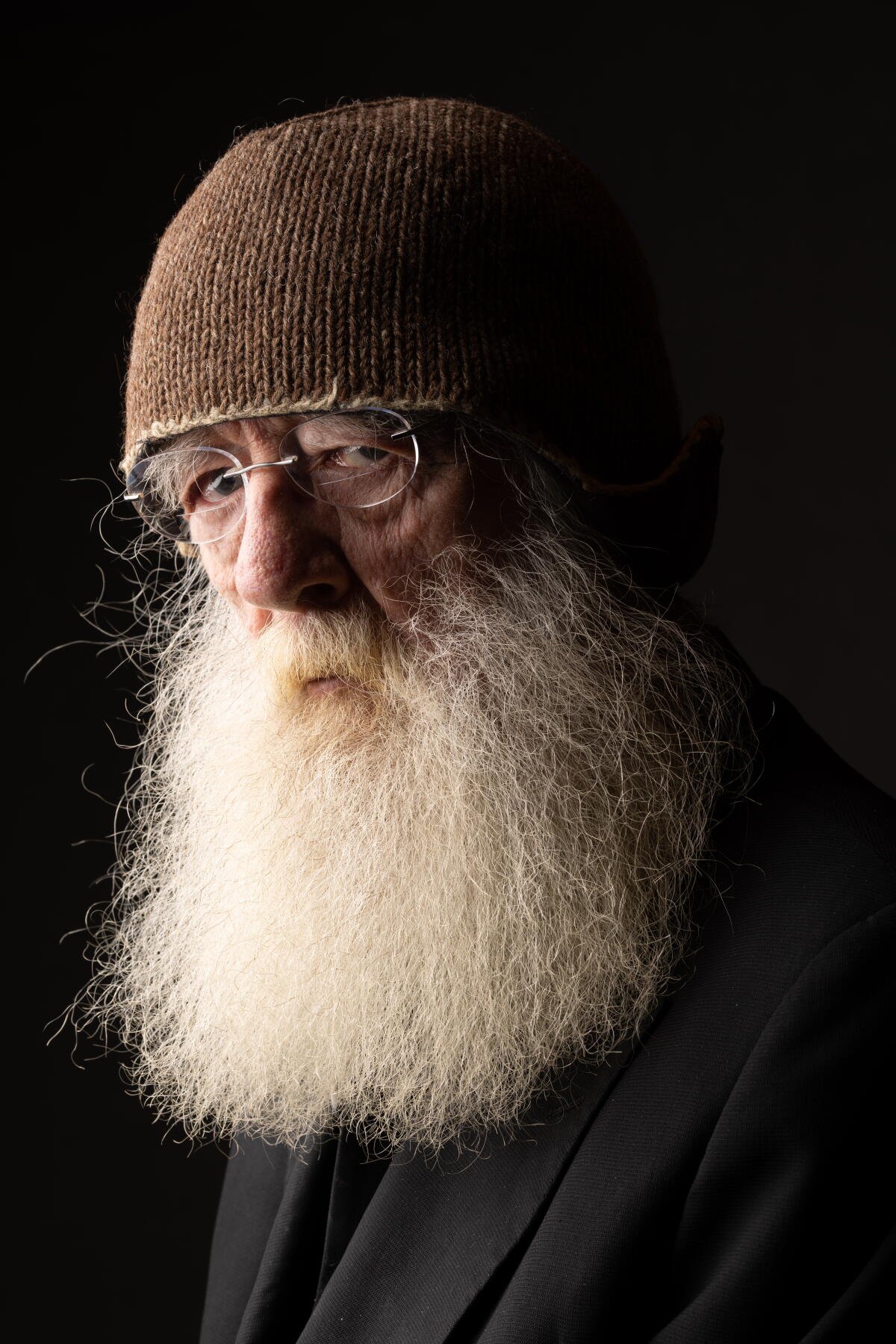 Godfrey Reggio, director of Koyaanisqatsi, in a portrait with a long white beard and knit cap
