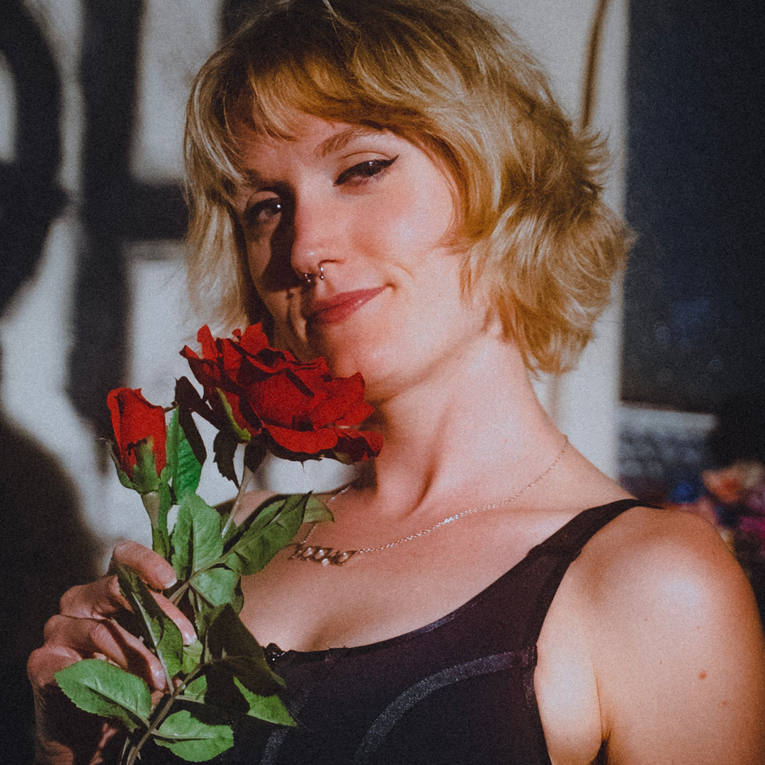 A performer holding red roses, from the Bushwick Comedy Club showcase lineup.