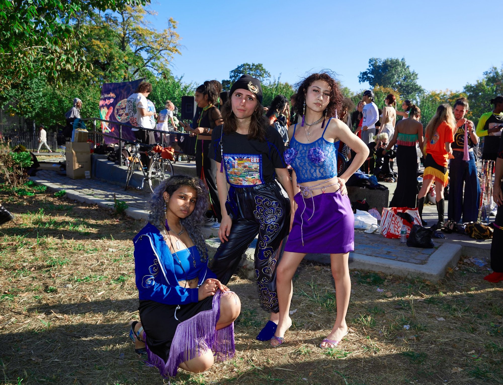 Three models stand in front of a crowd, a DJ speaker and an AMEHL banner in Maria Hernandez Park.